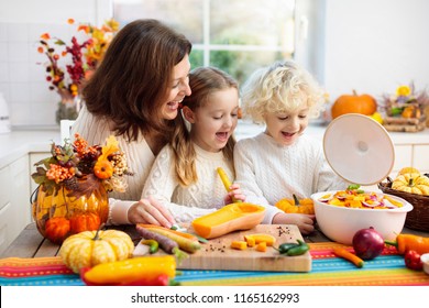 Mother And Kids Cutting Pumpkin, Onion And Carrot, Cooking Soup For Autumn Meal. Mom And Children Cook Healthy Fall Vegetables For Family Halloween Season Lunch. Boy And Girl Cut Squash In Kitchen.