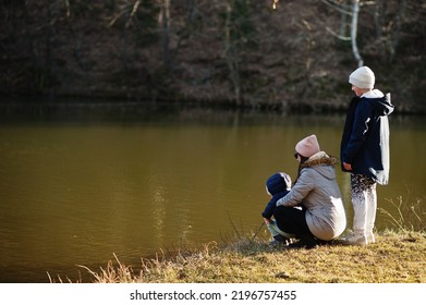 Mother With Kids Fishing With A Stick In Pound At Early Spring Park.