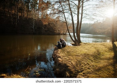 Mother With Kids Fishing With A Stick In Pound At Early Spring Park.