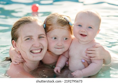 Mother And Kids Having Fun In The Swimming Pool. Summer Leisure And Family Holidays And Vacation Concept. People Swim In A Metal Frame Pool In The Backyard. Mom With Children: Baby Son And Daughter.