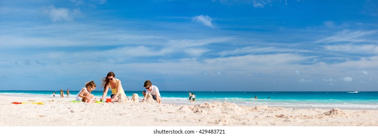 Mother and kids making sand castle at tropical beach