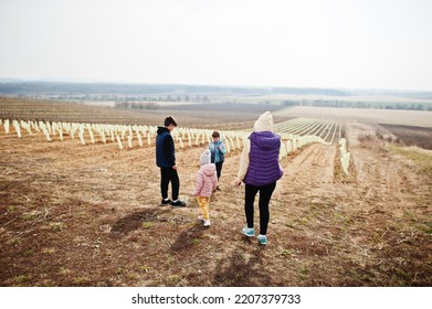 Mother With Kids Stand Against Vineyard In Early Spring.