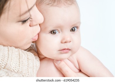 Mother kissing crying baby on a white background