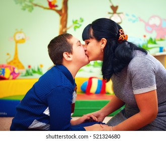mother kissing her beloved son with disability in rehabilitation center, soulful moment
