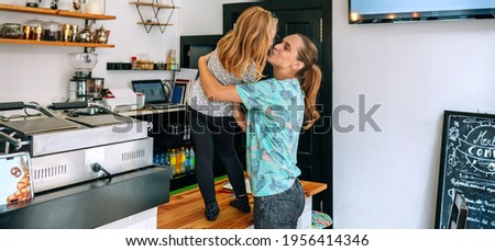 Mother kissing her daughter while working in a coffee shop. Reconciliation family life work concept