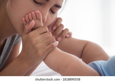 Mother Kissing On Newborn Baby Foot.