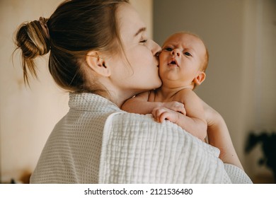 Mother kissing one month old baby on cheek.