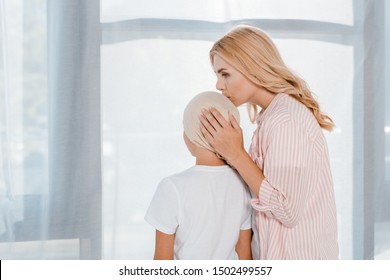 Mother Kissing Sick Child In Head Scarf At Home 