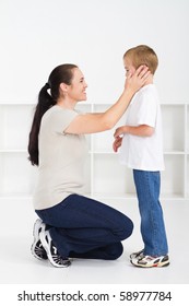 Mother Kneeling Down And Comforting Son Against White Background