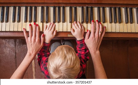 Mother learns baby to play piano
