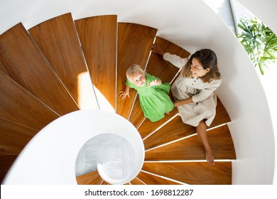 Mother And Little Baby Daughter Are Sitting On The Wooden Stairs Inside Of The House