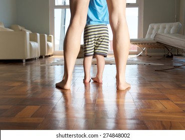 Mother And Little Boy Feet Standing On Wood Floor At Home