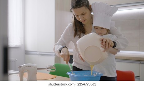 Mother and little child with cook hat cook together, blending, develop abilities - Shutterstock ID 2254793361