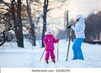 Mother And Little Child On Ski In City Park