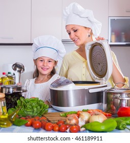 Mother And Little Daughter Cooking Veggies With Crockpot In Home Kitchen
