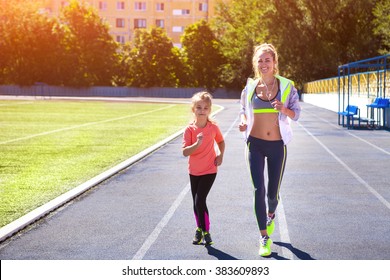 Mother and little daughter are doing exercise in the stadium. Family doing fitness at the stadium. Healthy family concept