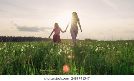 Mother and little daughter holding hands running in the green meadow toward the sun. Future and children concepts. - Powered by Shutterstock