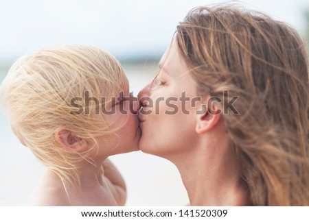 Mother and little daughter kissing on the beach