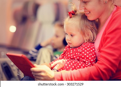 mother and little daughter looking at touch pad in plane, family travel - Powered by Shutterstock