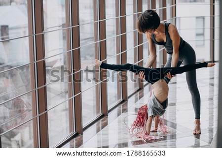 Mother with little daughter practicing yoga by the window