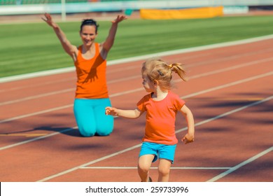 Mother & Little Daughter Running Around The Stadium. Child Runs Away From Mom At The Stadium. Toned.