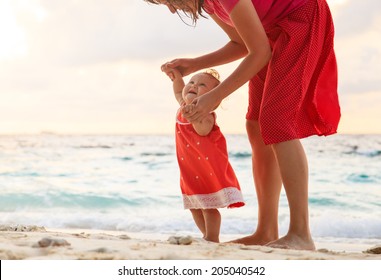 Mother And Little Daughter Walking On Sand Beach