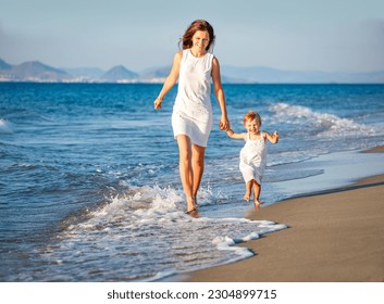 Mother and little daughter walking on the sea beach in Greece - Powered by Shutterstock