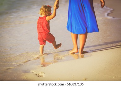 Mother And Little Daughter Walking On Beach