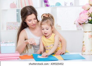 mother with little daughter in a yellow dress fun cut scissors colored paper