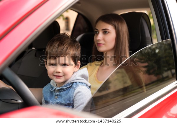 Mother with little son driving car together. Child\
in danger