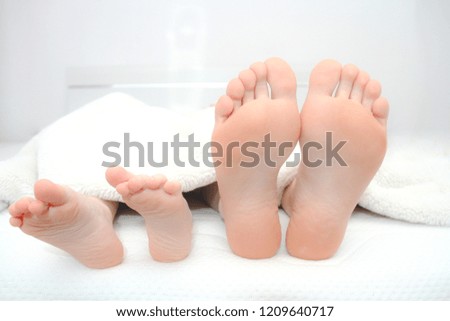 Mother and little son  laying on bed, their feets on focus