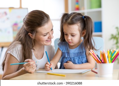 Mother looking how her child daughter drawing picture