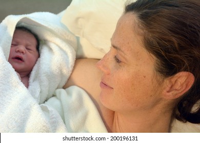 Mother Looks At Her Newborn Baby In Bed Immediately After A Natural Water Birth Labour. Concept Photo Of  Pregnant Woman, Newborn, Baby, Pregnancy.