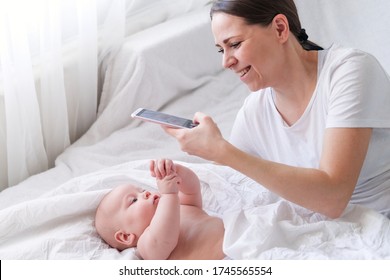 Mother Love. Caucasian Brunette Woman Mom Making Photo To Her Little Cutest Baby Lying In Bed. Infant Child. Mother And Baby. Happy Motherhood.