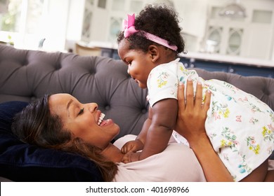 Mother lying back holding her toddler daughter on top of her