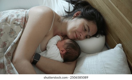 Mother lying in bed with newborn baby, cozy and intimate moment, mom watching over sleeping infant, serene family bonding, peaceful early morning, maternal love, nurturing environment, tender care - Powered by Shutterstock