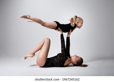 Mother lying down holding her daughter, she raised her hands imagining herself an airplane who loves to fly in the air