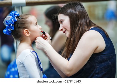 Mother Makes Make-up Her Daughter. Mother Putting Lipstick On Her Daughter On Mirror Background. Mom Helping Little Daughter To Use Lipstick Before A Dance Performance. Selective Focus.