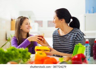 Mother Making Breakfast For Her Children In The Morning And A Snack For School At Home