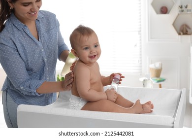 Mother Massaging Her Cute Baby With Oil On Changing Table At Home