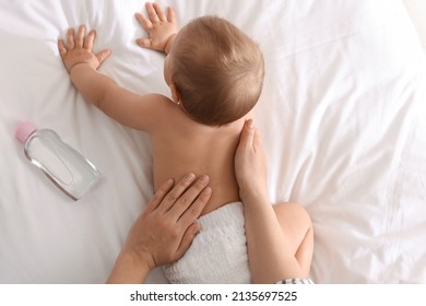 Mother massaging her cute baby with oil on bed, closeup - Shutterstock ID 2135697525