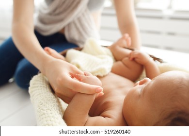 Mother massaging her newborn baby, close-up. Gymnastic, physical training, strengthening exercises for babies, early development, healthcare concept