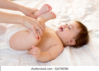 Mother or masseuer massaging baby girl in room