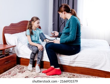 mother measuring blood pressure of the child. at home in bedroom Medical equipment. caucasian children cute or kid girl for health check with pressure gauge and pulse gauge at home.