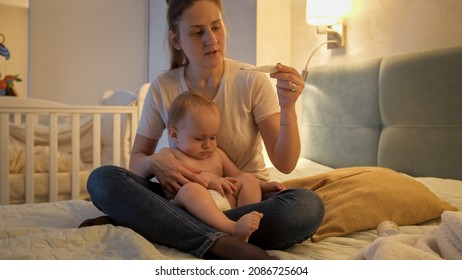 Mother Measuring Her Baby Boys' Body Temperature At Night. Sick Child At Home.