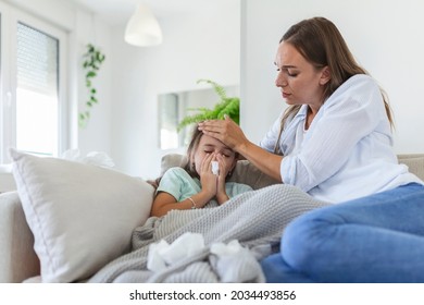 Mother measuring temperature of her ill kid. Sick child with high fever laying in bed and mother holding thermometer. Hand on forehead.