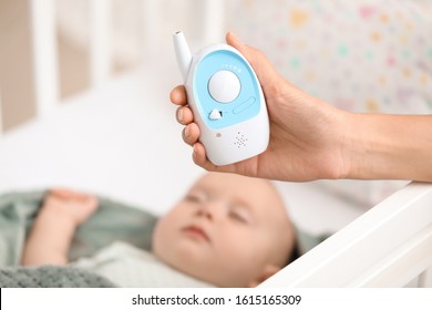 Mother With Modern Baby Monitor Near Bed With Sleeping Child