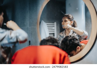 Mother multitasking in the bathroom, simultaneously getting ready and brushing her teeth while husband is washing his face.