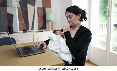 Mother multitasking with laptop and newborn baby, balancing work and childcare, indoors, casual setting, concerned expression, wearing black sweater, white blanket, modern home, daytime, family life - Powered by Shutterstock