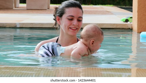 Mother and newborn baby son inside swimming pool water having fun
